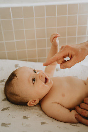 Bébé souriant pendant l’application du lait hydratant Fleurs de Peau