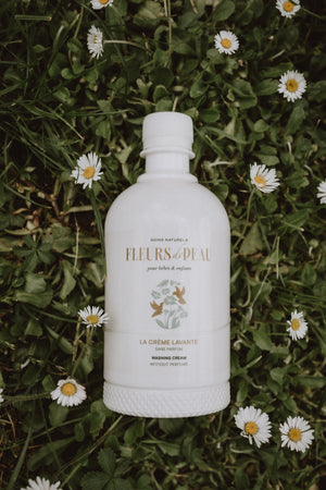 Bouteille de crème lavante Fleurs de Peau posée devant des fleurs