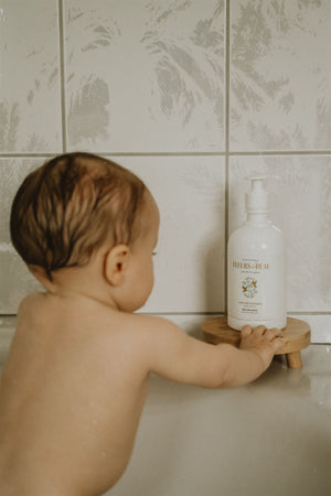 Bébé dans son bain avec eau nettoyante Fleurs de Peau posée sur un support