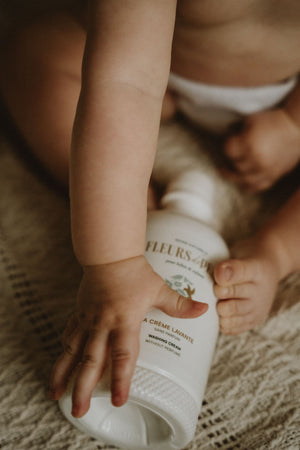 Bébé tenant la crème lavante Fleurs de Peau avec ses mains