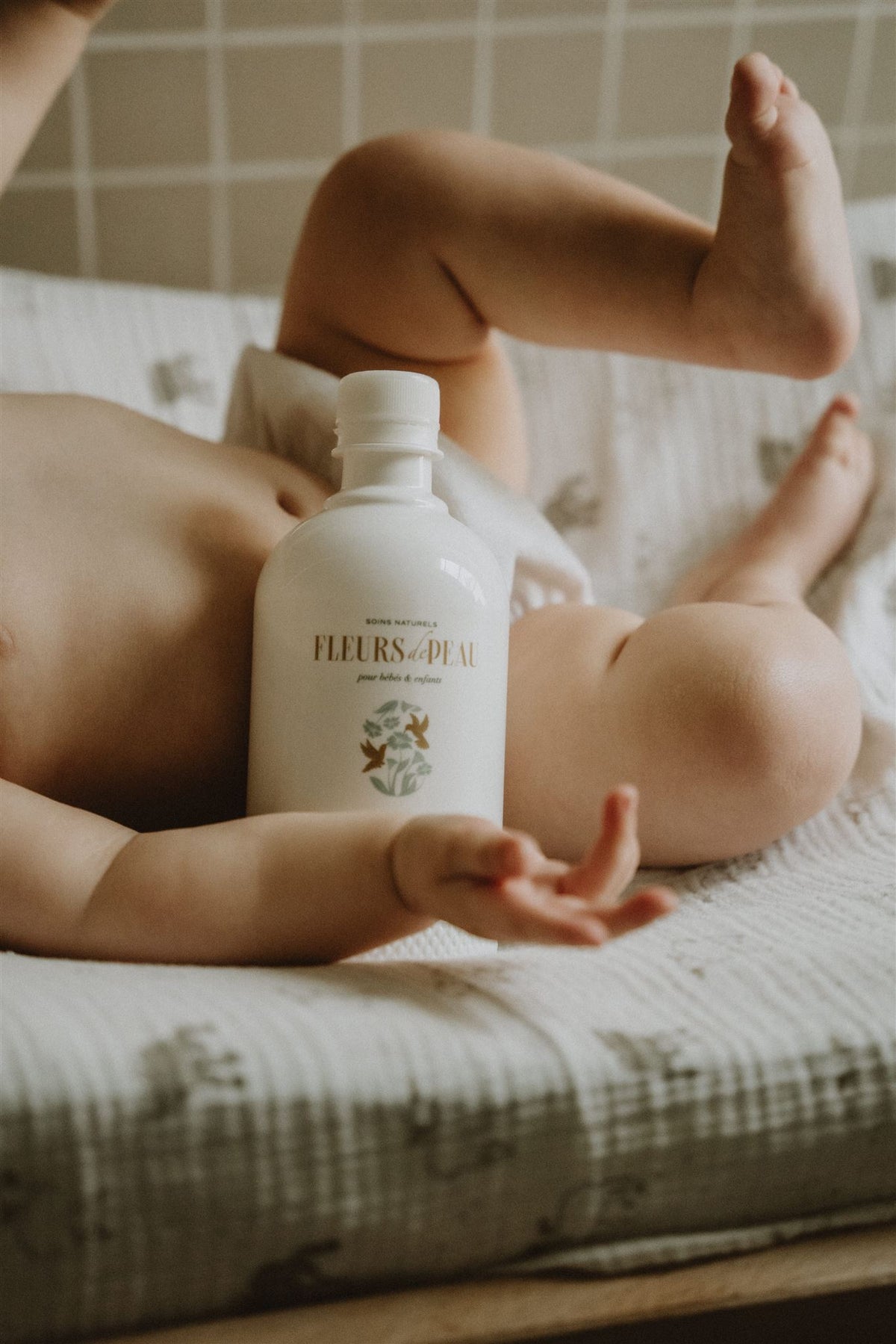 Bébé allongé tenant une eau nettoyante Fleurs de Peau