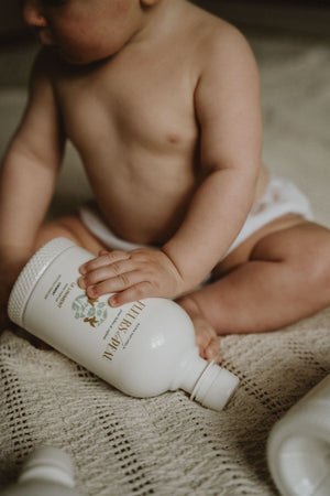Bébé tenant une bouteille de liniment Fleurs de Peau