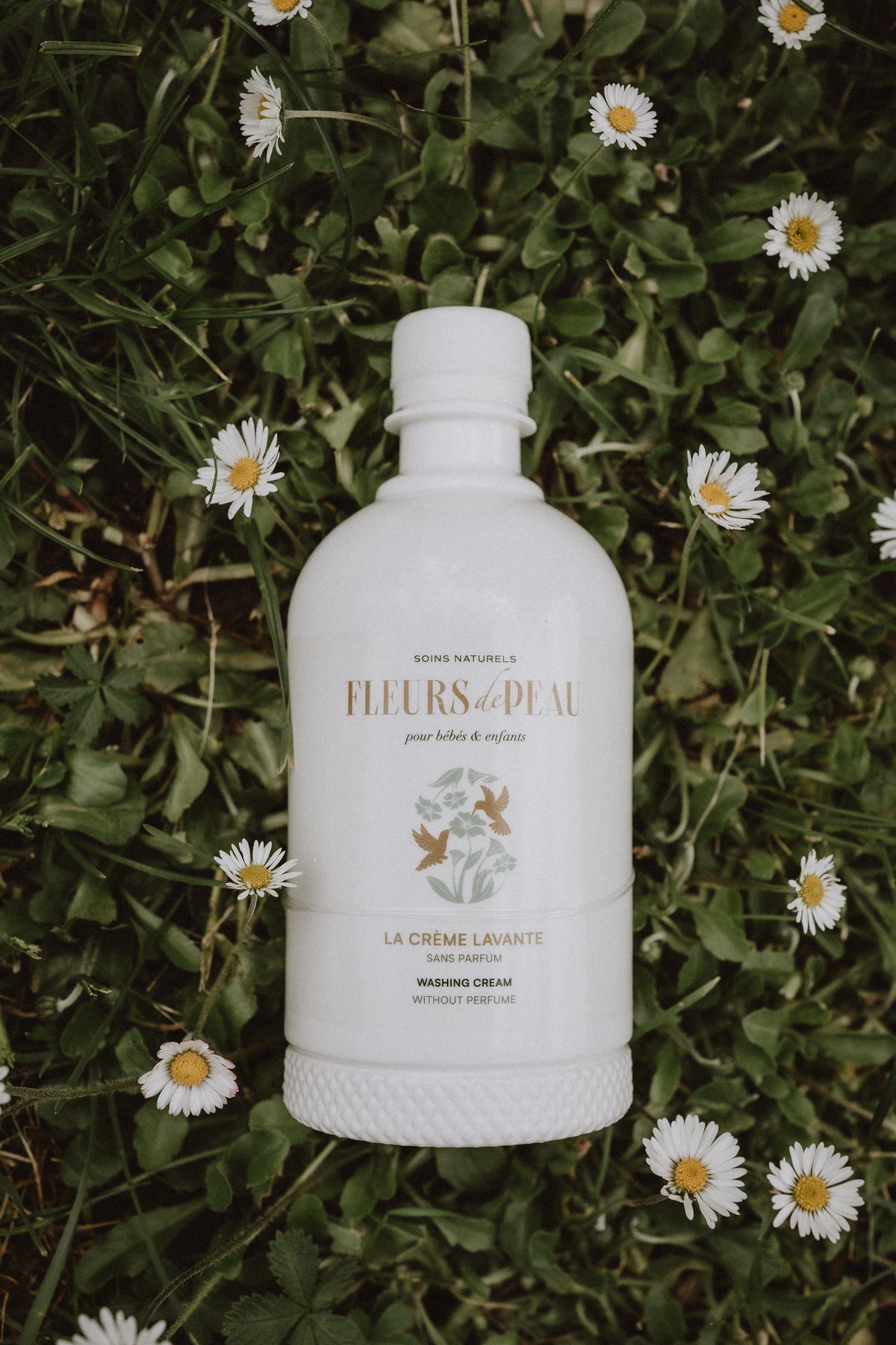 Bouteille de crème lavante Fleurs de Peau posée devant des fleurs
