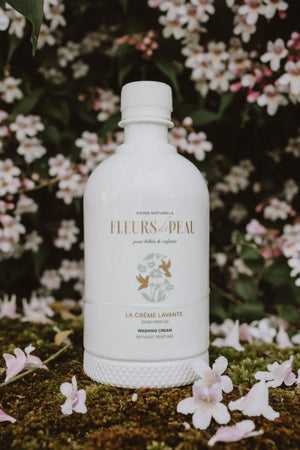 Flacon de crème lavante Fleurs de Peau sur un lit d’herbe avec des fleurs de printemps