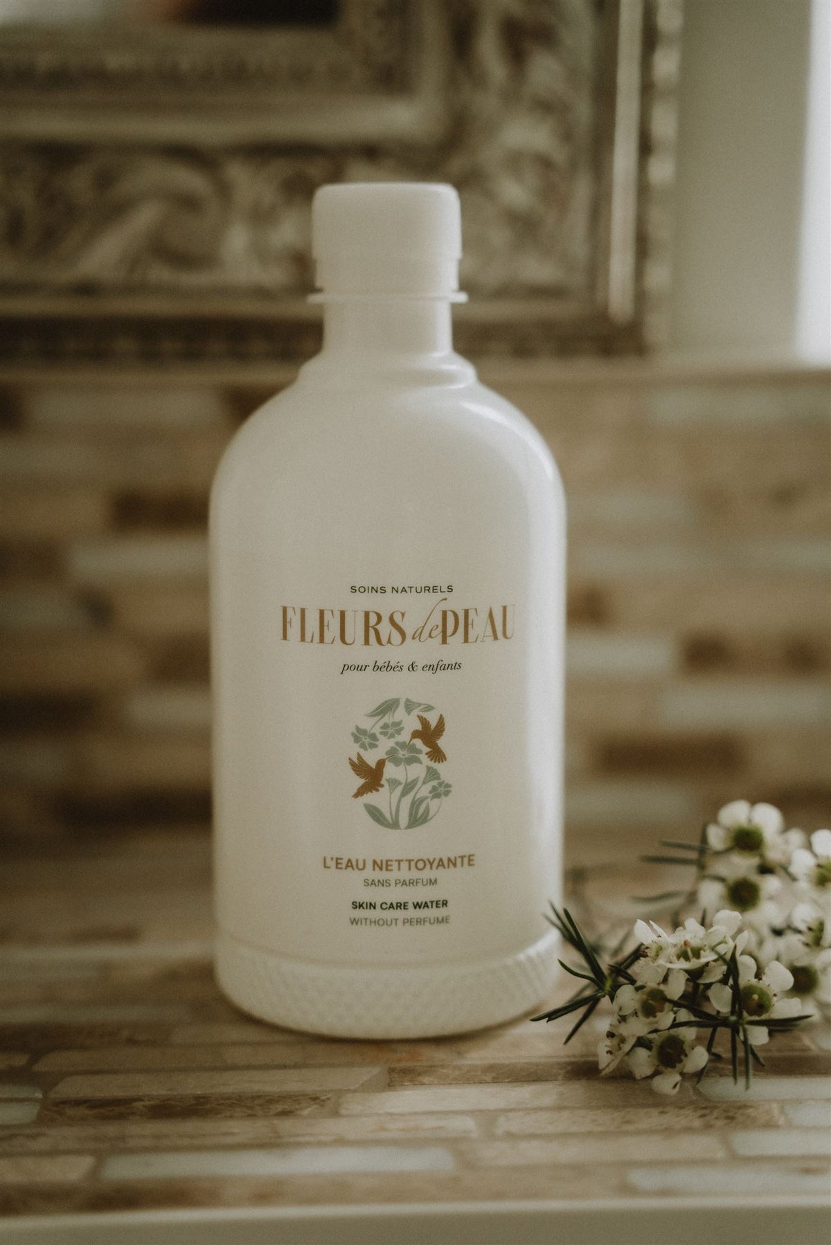 Eau nettoyante bébé Fleurs de Peau posée avec fleurs blanches