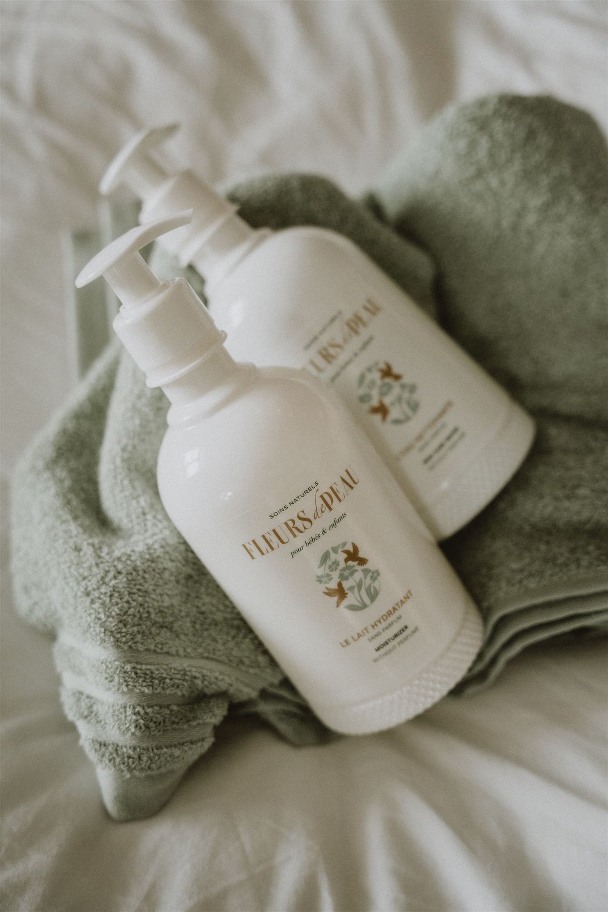 Deux flacons de lait hydratant Fleurs de Peau posés sur une serviette