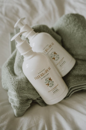 Deux flacons de lait hydratant Fleurs de Peau posés sur une serviette