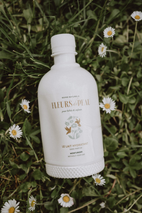 Lait hydratant Fleurs de Peau posé devant un fond fleuri