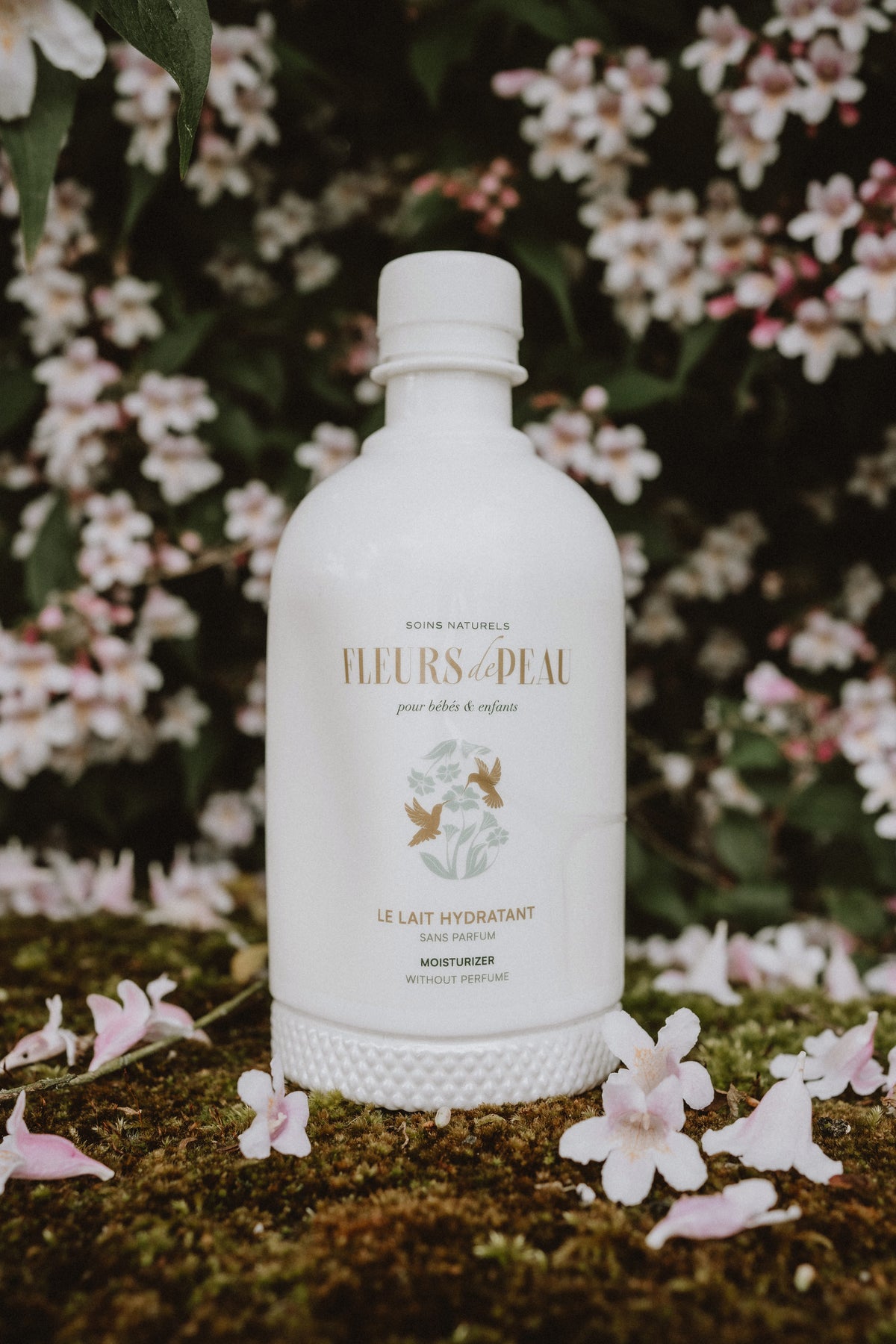 Flacon de lait hydratant Fleurs de Peau entouré de fleurs naturelles